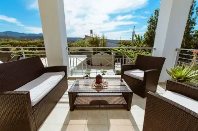 a patio with two chairs and a table on a balcony at Suite Erato in Kissamos