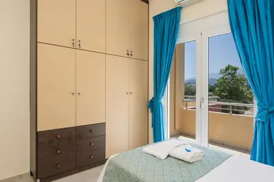 a bedroom with a bed with blue curtains and a window at AnnaBoutique Villa Next to Beach Private Pool & BBQ in Kato Daratso