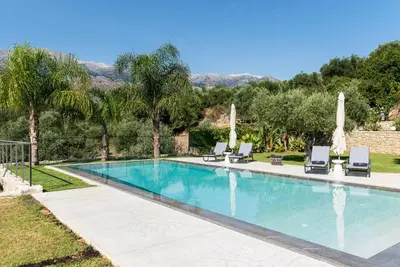 a swimming pool with two lounge chairs and a villa at Villa Inati in Nípos