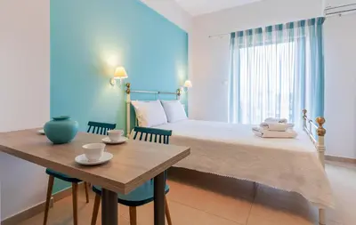 a bedroom with a bed and a table with two chairs at Kaiti 's Studios & Apartments in Palaiochóra