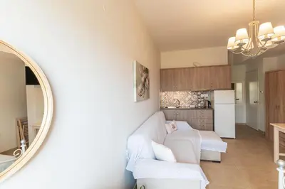 a living room with a white couch and a mirror at Kaiti 's Studios & Apartments in Palaiochóra