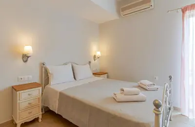 a white bedroom with a bed with towels on it at Kaiti 's Studios & Apartments in Palaiochóra