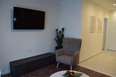 a living room with a chair and a flat screen tv at Downtown Delight in Chania Town