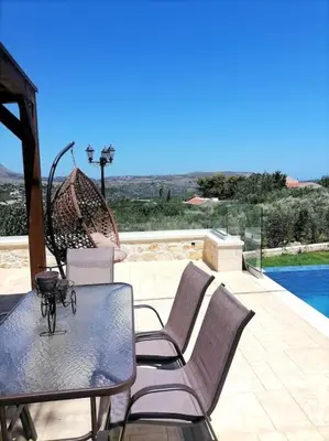 a table with chairs and an umbrella on a patio at VILLA HALEPOURI in Chania Town