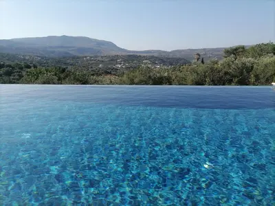 a pool of blue water with mountains in the background at VILLA HALEPOURI in Chania Town