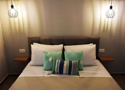 a bed with three pillows and two lights above it at Olgas cozy home in Chania Town