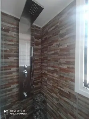 a bathroom with a shower with a wooden wall at Souda Bay in Souda