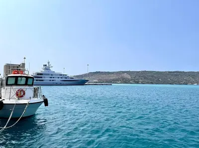 a boat in the water next to a cruise ship at Souda Bay in Souda