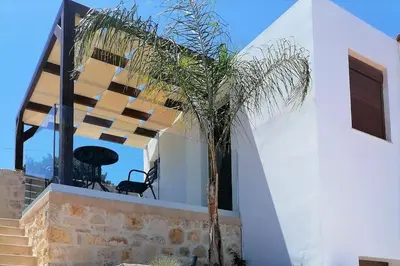 a palm tree in front of a white house at Halepouri Apartment in Chania Town