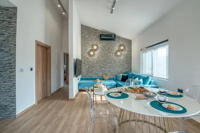 a living room with a table and a blue couch at Alyona Villas - Villa Lona in Skinés