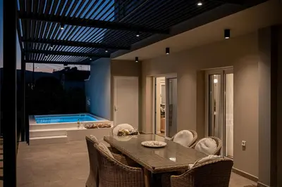 a dining room with a table and chairs and a swimming pool at HappyHouse Villa in Kissamos