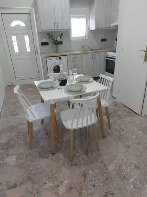 a kitchen with a white table and chairs and a white refrigerator at Maria's sala in Kissamos