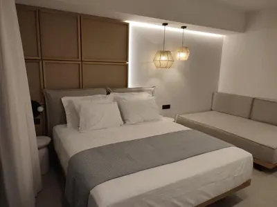 a bedroom with a large bed and a couch at Ammos Paleochora Hotel in Palaiochóra