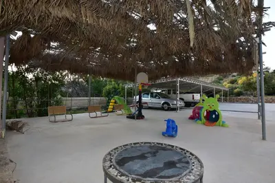 a patio with a table and chairs and a straw umbrella at Morpheas Rooms in Palaiochóra