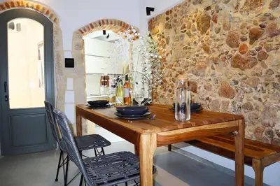 a dining room with a wooden table and a stone wall at Porto 57 in Chania Town