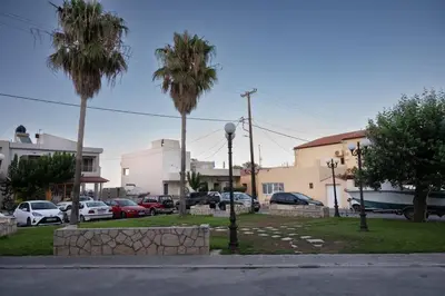 a parking lot with palm trees and parked cars at Perion stone apartment sea front in Kolymvari