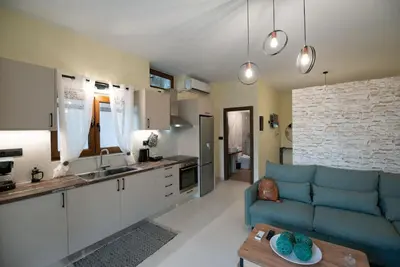 a living room with a blue couch and a kitchen at Perion stone apartment sea front in Kolymvari