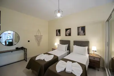 a bedroom with two beds and a mirror at Perion stone apartment sea front in Kolymvari