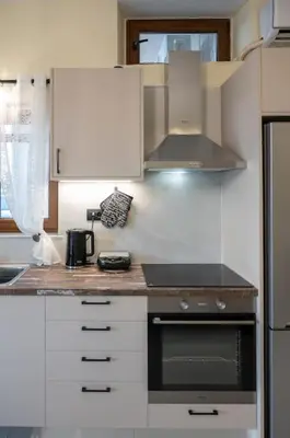 a kitchen with white cabinets and a stove top oven at Perion stone apartment sea front in Kolymvari