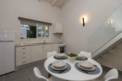 a white kitchen with a white table and chairs at El Greco Studios in Agia Marina Nea Kydonias