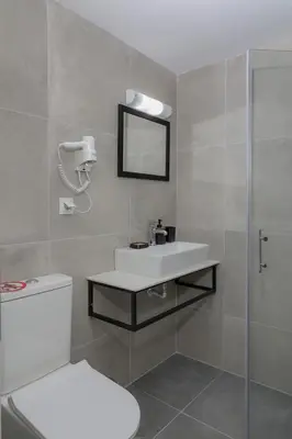 a bathroom with a sink and a toilet and a mirror at El Greco Studios in Agia Marina Nea Kydonias