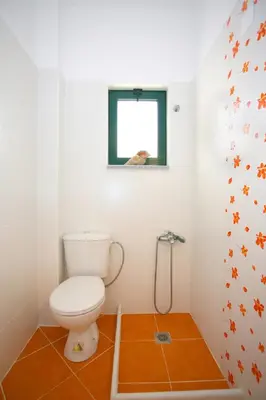 a bathroom with a toilet and a window at Aptera Paradise With Sea View in Megála Khoráfia