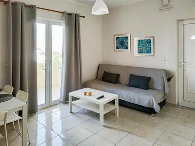 a living room with a couch and a table at Pasithea apts in Almirida