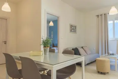 a dining room and living room with a table and chairs at Pasithea apts in Almirida