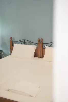 a bed with white sheets and two pillows at Pasithea apts in Almirida
