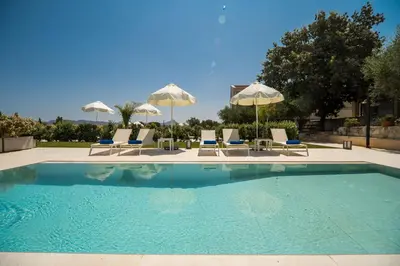 a swimming pool with chairs and umbrellas at Aelia by PosarelliVillas in Kounoupidhianá