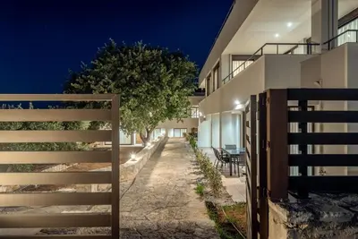 a fence in front of a house at night at Aelia by PosarelliVillas in Kounoupidhianá