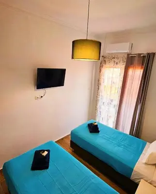 two beds in a room with a tv on the wall at Erofili central apartment in Chania Town