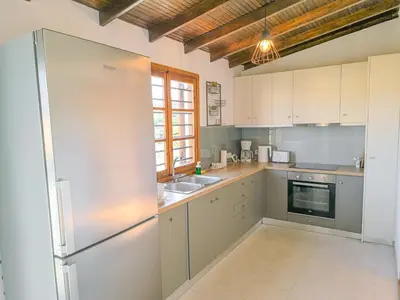 a kitchen with white cabinets and a stainless steel refrigerator at Charming house 8 minutes walk from Almyrida beach in Almirida