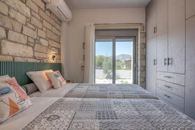 a bedroom with a large bed and a stone wall at Gramvousa's Hidden Gem in Áyios Yeóryios