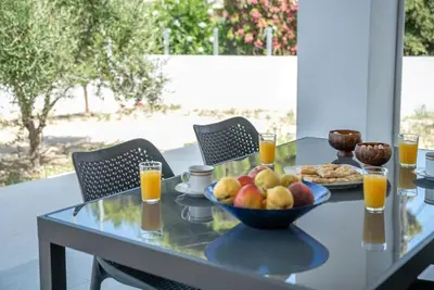 a glass table with a bowl of fruit and orange juice at Gramvousa's Hidden Gem in Áyios Yeóryios