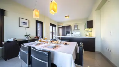 a dining room with a table and chairs and a kitchen at Villa Majestic Crete heated pool and sauna in Megála Khoráfia