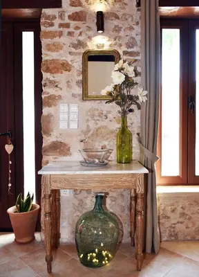 a table with a vase of flowers and a mirror at ESTIA stone house in Vrísai