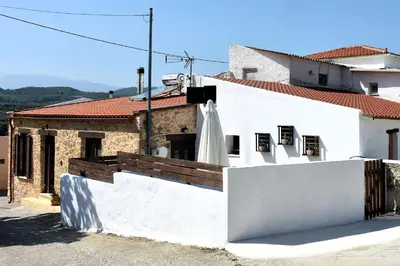 a white building with a balcony with a roof at ESTIA stone house in Vrísai