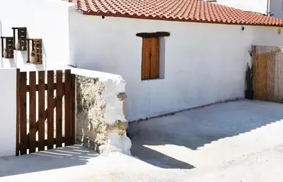 a white house with a wooden door and a fence at ESTIA stone house in Vrísai