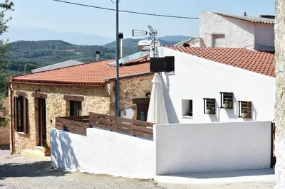 a white building with a white umbrella in front of it at ESTIA stone house in Vrísai