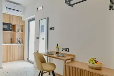 a kitchen with a table with a chair and a bowl of fruit at Orfeas Apartment in Chania Town