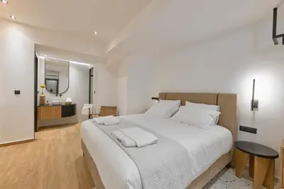 a bedroom with a large white bed and a bathroom at Evridiki Apartment in Chania Town