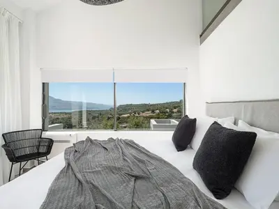a white bedroom with a bed and a large window at Sunny Vacay Villa in Stérnai