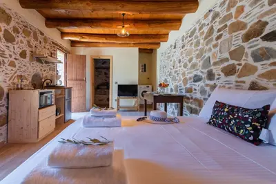 a bedroom with a stone wall and a bed with pillows at Plagia Rooms in Kissamos