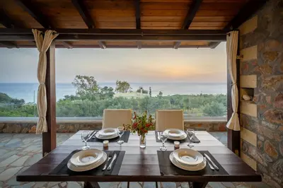 a dining room with a table and a large window at Blue Pearl Villa in AmigdhalokeFálion