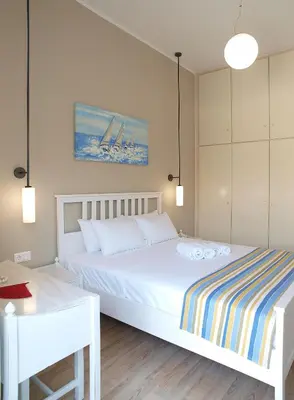 a bedroom with a white bed and a table and a desk at Almiris Seaside Apartments in Almirida