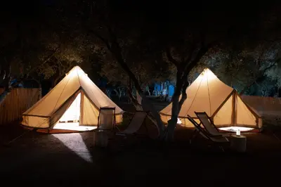 a couple of tents sitting under trees at night at Camping Chania in Kato Daratso