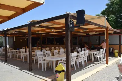 a group of tables and chairs under a pavilion at Camping Chania in Kato Daratso