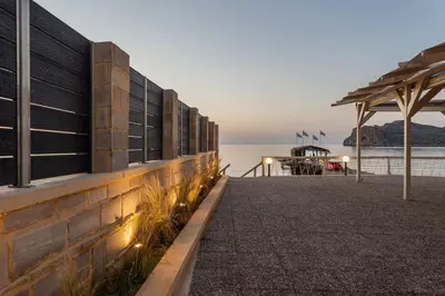 a walkway next to the water with a pier at Celeste Junior Suite on the Beach in Agia Marina Nea Kydonias