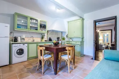 a kitchen with green cabinets and a table and chairs at Casa Ari - Venetian Port in Chania Town